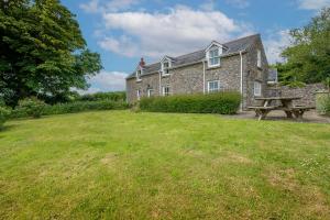 a stone house with a picnic table in the yard at Castle View in Carew