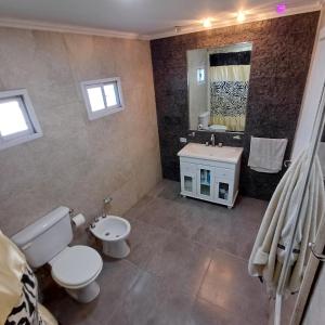 a bathroom with a toilet and a sink and a mirror at Ideal CASA EN NECOCHEA in Necochea