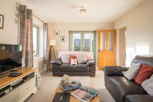 ein Wohnzimmer mit einem Ledersofa und einem TV in der Unterkunft Skylark Cottage in Haverfordwest