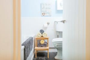 ein Badezimmer mit einem WC und einem Regal mit Handtüchern in der Unterkunft Swiss Cottage in Tenby + 32 Fotos