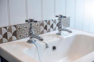 a bathroom sink with two faucets on it at 2 Penally Boathouse Mews in Cardigan +29 photos