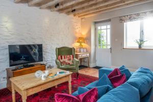 a living room with a blue couch and a tv at Smithies Cottage in Saint Brides
