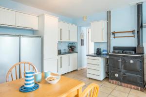 kuchnia z białymi szafkami i drewnianym stołem w obiekcie Blueberry Cottage w mieście Haverfordwest