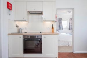 a kitchen with white cabinets and a stove top oven at Agos Y Mor in Haverfordwest +25 photos