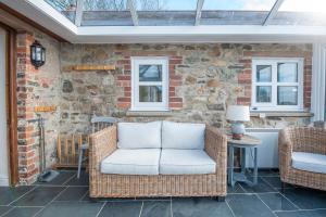una silla de mimbre sentada en un patio con una pared de piedra en Felin Fach, en Haverfordwest
