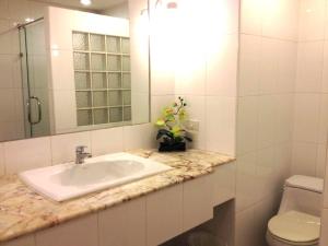 a white bathroom with a sink and a toilet at Raya Grand Hotel in Nakhon Ratchasima