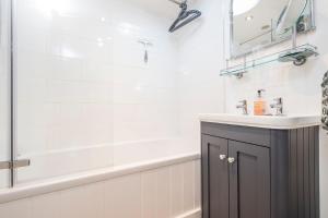a bathroom with a tub and a sink and a mirror at 1 Penally Boathouse Mews in Cardigan