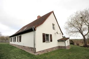 una casa bianca con finestre marroni su un prato di Haus am See - zur blauen Tür a Templin