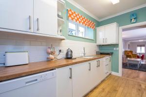 eine Küche mit weißen Schränken und Arbeitsflächen aus Holz in der Unterkunft Inkerman House in Saundersfoot