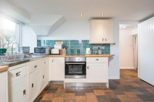 a kitchen with white cabinets and a stove top oven at Drws Gobaith-West in Haverfordwest