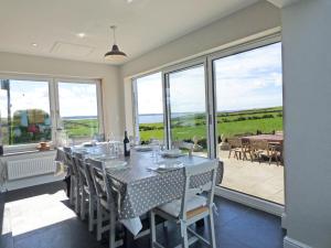 Un comedor con mesa y sillas y ventanas. en Lower Folly, en Haverfordwest