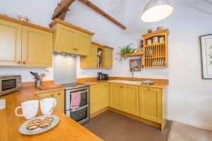 eine Küche mit gelben Schränken und ein Tisch mit einem Teller Essen in der Unterkunft Weavers Cottage in Lampeter-Velfrey + 28 Fotos