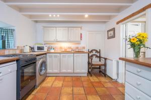 eine Küche mit weißen Schränken und einer Vase aus Blumen in der Unterkunft Honeysuckle Cottage in Solva + 21 Fotos