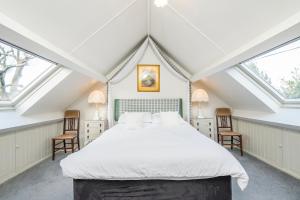 1 Schlafzimmer mit einem großen weißen Bett mit 2 Stühlen in der Unterkunft Honeysuckle Cottage in Solva