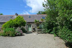 ein Steinhaus mit einer grünen Tür und einem Garten in der Unterkunft Honeysuckle Cottage in Solva