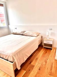 a white bed in a room with a wooden floor at Appartment Milano in Milan