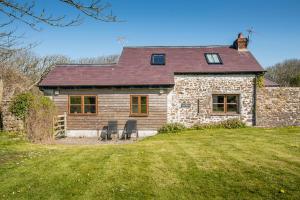 une maison en pierre avec deux chaises devant dans l'établissement Nolton Coach House, à Haverfordwest