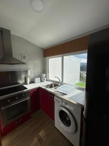 a kitchen with a sink and a washing machine at PortoHome Ático in Portomarin