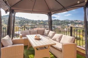 eine Terrasse mit einem Sofa und einem Tisch mit einem Sonnenschirm in der Unterkunft Villa Luz Lloret Lux with Pool in Lloret de Mar
