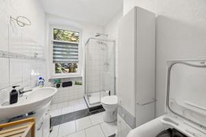 a white bathroom with a sink and a shower at Schöne Erdgeschoss-FeWo für 4 Personen in Halberstadt +10 photos