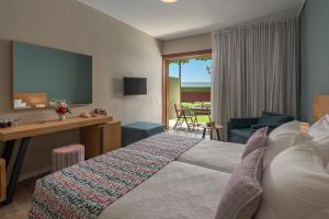 a hotel room with a bed and a desk and a television at Skiathos Palace Hotel in Koukounaries