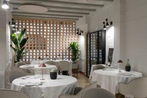 a restaurant with white tables and chairs and a large window at Hotel Palacio Barón de Andilla in Valdealgorfa