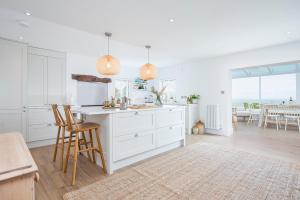 Una cocina con gabinetes blancos y una mesa y sillas. en Ty Perci Penrhiw, en Dinas