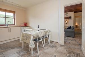 Una cocina con una mesa con sillas y una botella de vino. en Coastal View, en Haverfordwest