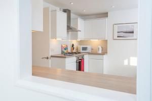 Una cocina con gabinetes blancos y un horno de estufa. en Awel Y Mor, en Newport 15 fotos más