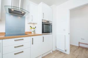 Una cocina con gabinetes blancos y una estufa. en Sandy-Rise, en Haverfordwest