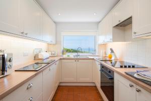 a kitchen with white cabinets and a window at Tan Y Bryn in Haverfordwest