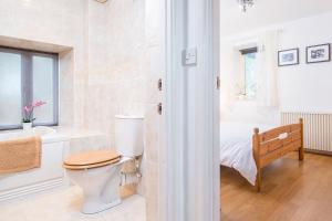 a bathroom with a toilet and a sink and a bed at Picture Cottage in Solva