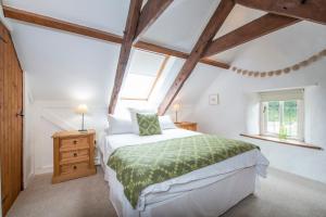 a bedroom with a bed with a green comforter and two windows at The Old Dairy in Haverfordwest