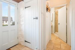 einen Flur mit einer weißen Tür und einem Fenster in der Unterkunft Little Rogeston Cottage in Haverfordwest + 19 Fotos