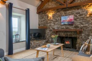 Una sala de estar con una pared de piedra con chimenea. en Little Folly, en Haverfordwest