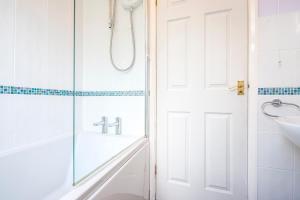 a white bathroom with a shower and a sink at Cwtch Cottage in Haverfordwest