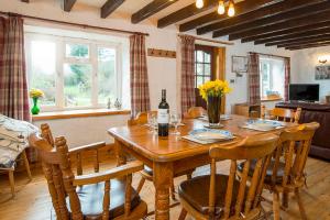 ein Esszimmer mit einem Holztisch und einer Flasche Wein in der Unterkunft Honey Hook Cottage in Haverfordwest