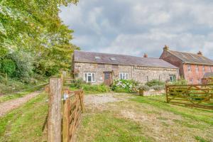 ein altes Steinhaus mit einem Zaun davor in der Unterkunft Honey Hook Cottage in Haverfordwest