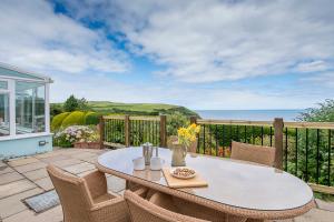 Una mesa y sillas en un patio con vista al mar. en Ty Perci Penrhiw, en Dinas