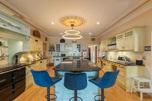 a large kitchen with blue chairs and a large island at Waterwynch House in Tenby