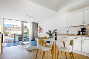 a kitchen and living room with a table and chairs at Morasol Suites in Puerto Rico de Gran Canaria