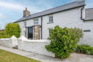 een wit huis met een stenen hek ervoor bij Ty Canol in Goodwick