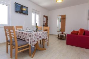 salon ze stołem i czerwoną kanapą w obiekcie Apartments Zvone1 w mieście Veli Rat