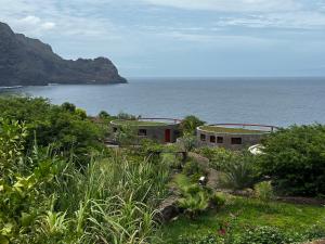 a house on a hill next to the ocean at Palmeira Da Cruz EcoLodge in Chã da Igreja