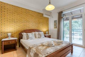 a bedroom with a bed and a brick wall at Kaminaki Villas by Tsiolis Family in Katávolos