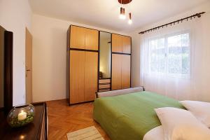 um quarto com uma cama verde e uma grande janela em Ana Apartment em Rabac