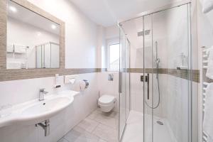 a white bathroom with a sink and a shower at Hotel Schachenwald I Sauna I Aussenpool I Parkplatz in Premstätten