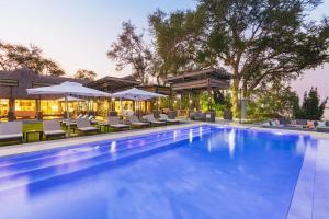 a swimming pool with lounge chairs and umbrellas at Chobe Water Villas in Kasika