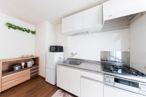 a kitchen with white cabinets and a sink at Kosumosu in Tokyo