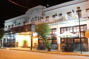 a hotel with tables and umbrellas in front of it at Hotel Lopes Caxambu in Caxambu